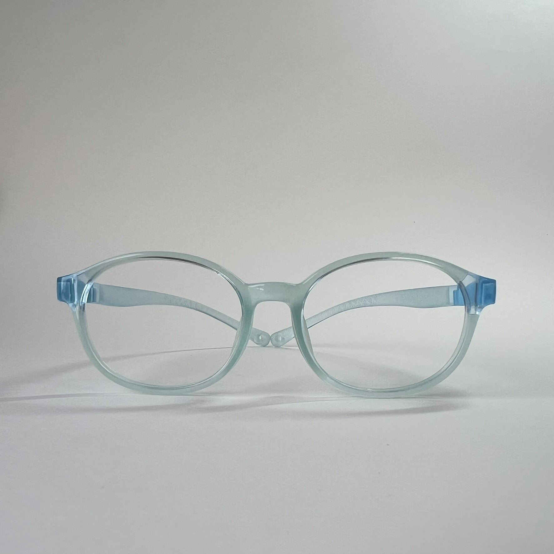 PureFlex kids flexible glasses in translucent jelly blue silicone material, showcasing the specialized wrap-around curved temple arms for ages 7-9. Front view.