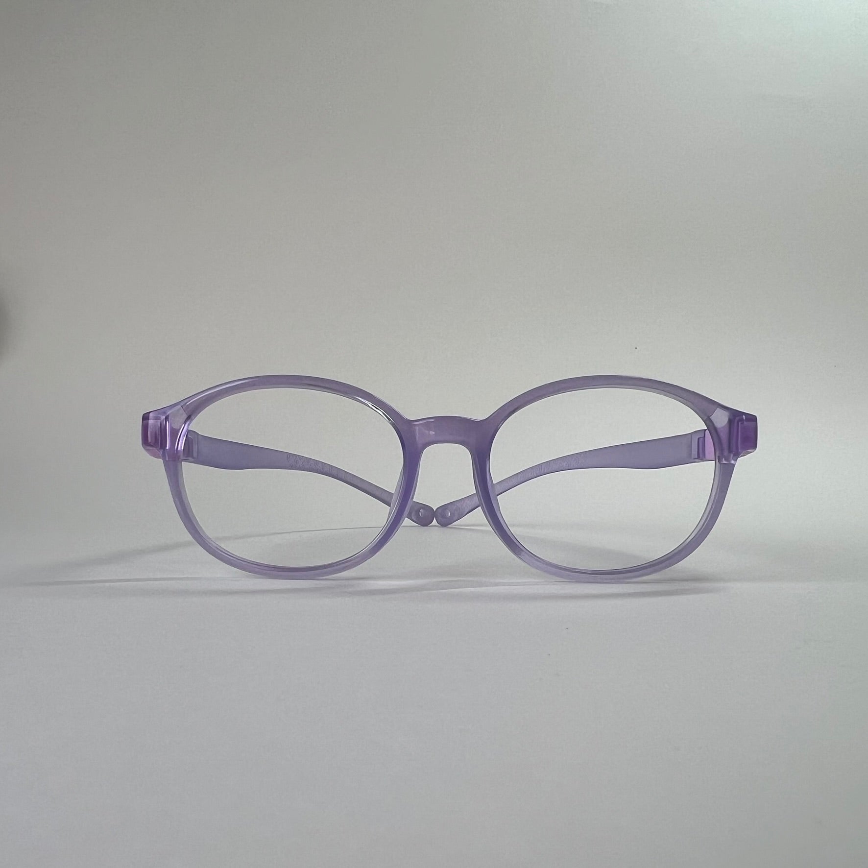 PureFlex kids flexible glasses in translucent jelly purple silicone material, showcasing the specialized wrap-around curved temple arms for ages 7-9. Front view.
