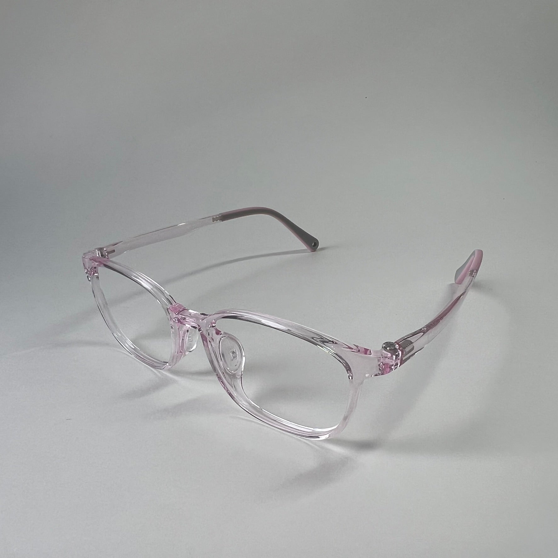 MiniMuse clear jelly pink rounded square prescription glasses for kids and tweens with silicone nose pads and adjustable temple tips. Side view.
